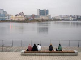 People sit on a bench on an autumn day and admire the surface of the lake. photo