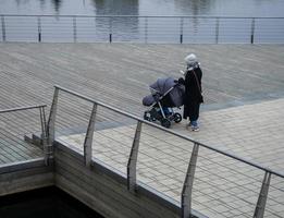 A woman on a walk with a stroller looks at the phone. photo