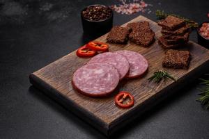 Delicious fresh smoked sausage cut with slices on a wooden cutting board photo