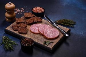 Delicious fresh smoked sausage cut with slices on a wooden cutting board photo