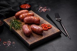 Grilled sausages with spices and herbs on a black background photo