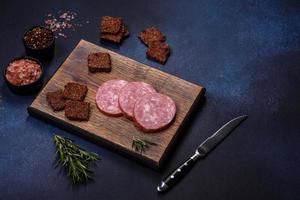 Delicious fresh smoked sausage cut with slices on a wooden cutting board photo
