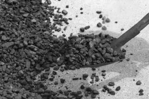 Black coal on a shovel, against the background Heaps of black coal. Energy Crisis. Soft focus. photo