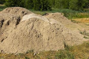 una montaña de arena en un sitio de construcción. material de base el suelo está preparado para fortalecer el suelo. montón de tierra. arena fina para nivelar y rellenar foto