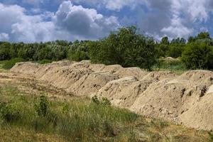 Construction sand. Mountain of sand on construction site. Excavated earth. Preparation of foundation for road. photo