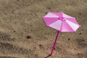 Playground, Children's sandbox, Toy umbrella in pink and white colors on a sandy beach by the sea. Children's psychedelic. Selective focus. photo