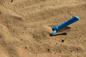 Children's sandbox, plastic toy children's shovel of blue color on a sandy beach by the sea. Children's psychedelic. selective focus. photo