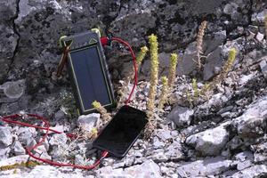 Smartphone and mobile, portable charger on a solar panel. The concept of being connected while traveling. photo