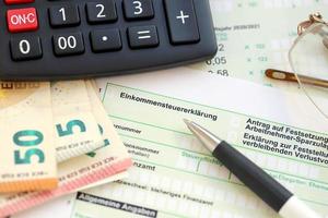 German income tax return form with pen and european euro money bills lies on accountant table close up. Taxpayers in Germany using euro currency to pay taxes photo