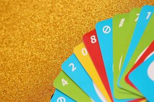 TERNOPIL, UKRAINE - MAY 15, 2022 Many colorful UNO game cards on golden background. UNO is an American shedding-type card game that is played with a specially printed deck photo