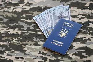 Ukrainian foreign passport on fabric with texture of military pixeled camouflage. Cloth with camo pattern in grey, brown and green pixel shapes and Ukrainian ID photo