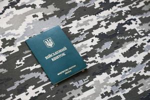 Ukrainian military ID on fabric with texture of pixeled camouflage. Cloth with camo pattern in grey, brown and green pixel shapes with Ukrainian army personal token photo