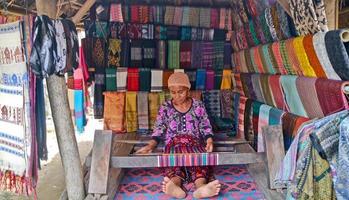 pueblo de sade, lombok, indonesia, junio de 2021- una mujer teje hilo para usar como sesek foto