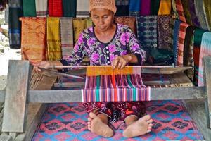 Sade Village, Lombok, Indonesia, June 2021- A woman weaves yarn to be used as sesek photo