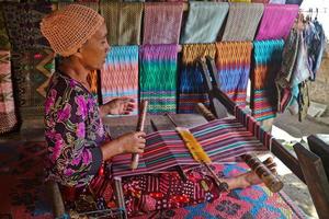 Sade Village, Lombok, Indonesia, June 2021- A woman weaves yarn to be used as sesek photo