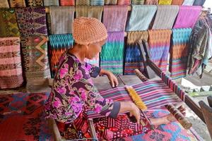 Sade Village, Lombok, Indonesia, June 2021- A woman weaves yarn to be used as sesek photo