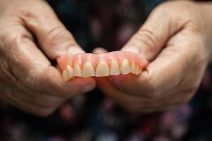 Paciente anciana o anciana asiática que sostiene que usa dentadura postiza en la sala del hospital de enfermería, concepto médico fuerte y saludable. foto