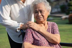 Caregiver help and care Asian senior or elderly old lady woman patient sitting on wheelchair in park, healthy strong medical concept. photo