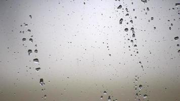 Rainy day raindrops on window as relaxing background texture for autumn and fall season shows rain and water droplets splashing on window surface with rainy weather texture in depression mood video