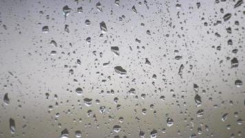 gotas de chuva de dia chuvoso na janela como textura de fundo relaxante para outono e outono mostra gotas de chuva e água espirrando na superfície da janela com textura de tempo chuvoso em humor de depressão video