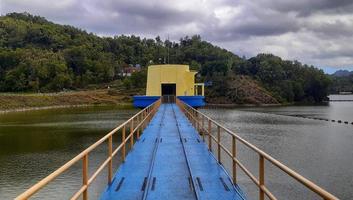 Yogyakarta, Indonesia, September 15, 2022 The building is in the middle of the lake with hills and clouds in the background. This building is used to put the lake irrigation machine. photo