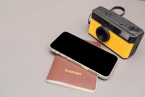 concepto de viaje cámara vintage, teléfono inteligente, pasaporte, sobre fondo gris, con espacio de copia. foto