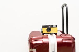 Travel Concept vintage camera on red luggage gray background, with copy space. Suitcase and retro film camera travel concept. photo