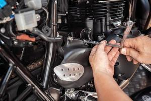 Mechanic using a Y Shape Wrench to Remove front sprocket cover on motorcycle, working in garage .maintenance and repair motorcycle concept .selective focus photo