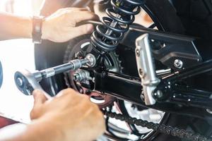 Mechanic using a wrench and socket to Remove and Replace Adjustable Rear Motorcycle Suspension, working in garage maintenance, repair motorcycle concept .selective photo