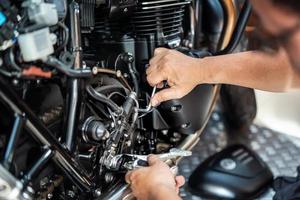 mecánico que usa una llave hexagonal o una llave allen para quitar la bomba de freno hidráulica trasera de la motocicleta, trabajando en el garaje. concepto de mantenimiento y reparación de motocicletas. enfoque selectivo foto