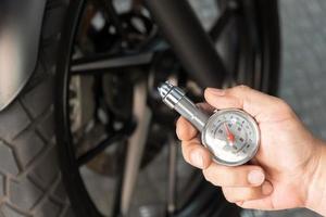 Man holding pressure gauge for checking  motocycle tyre pressure ,maintenance,repair motorcycle concept in garage .selective focus photo