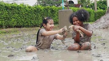 Due ragazze giocare nel fango e catturare rane. all'aperto apprendimento al di fuori il aula video