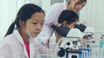 las colegialas asiáticas están estudiando ciencia y tecnología en un laboratorio. los maestros enseñan ciencias a los estudiantes para aprender habilidades de proceso. video