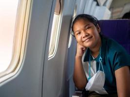 Asian woman smiling at the window of an airplane photo