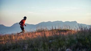 A young sportsman runs at sunset in the hills photo