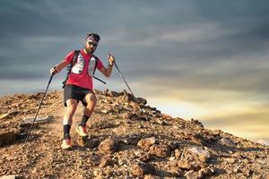 hombre deportivo desciende del pico rocoso foto