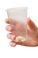 vaso de plástico con dosis de pastillas en la mano aislado foto