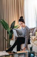 Online merchandising business idea, a beautiful girl is using a computer to check orders to deliver parcels to customers according to orders received from customers. photo