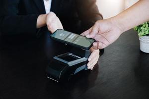 Payment security technology concept and service fees, Employees are holding electronic card machines for customers to use smartphone mobile to pay via paywave technology. photo