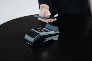 concepto de tecnología de pago seguro y cargo por servicio, los clientes están usando su teléfono para pagar usando tecnología paywave tocando cerca de la terminal de tarjeta electrónica. foto