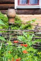 wattle fence with clay crock and country house photo