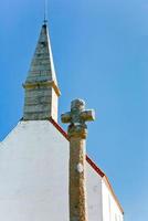antigua cruz de piedra y techo de capilla rural con fondo de cielo azul foto
