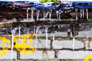 icicles on old gully of house with brick wall photo