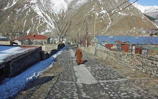 mujer caminando por una carretera en la ciudad de montaña de kazbegi, georgia foto