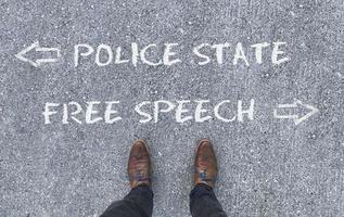 Top view on a man standing in front of the words Police State and Democracy with arrows pointing to the left and right side of the picture photo