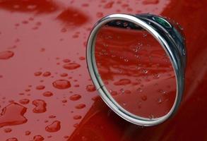 Selective focus on rain drops on top of a red car photo