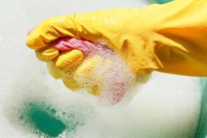 hand in yellow rubber glove wrings out wet duster photo