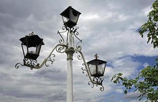 Old broken street lights against a cloudy sky photo