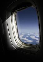 The sun shines through a plane window at cruising altitude photo