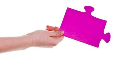 mano femenina sosteniendo una gran pieza de rompecabezas de papel rosa foto